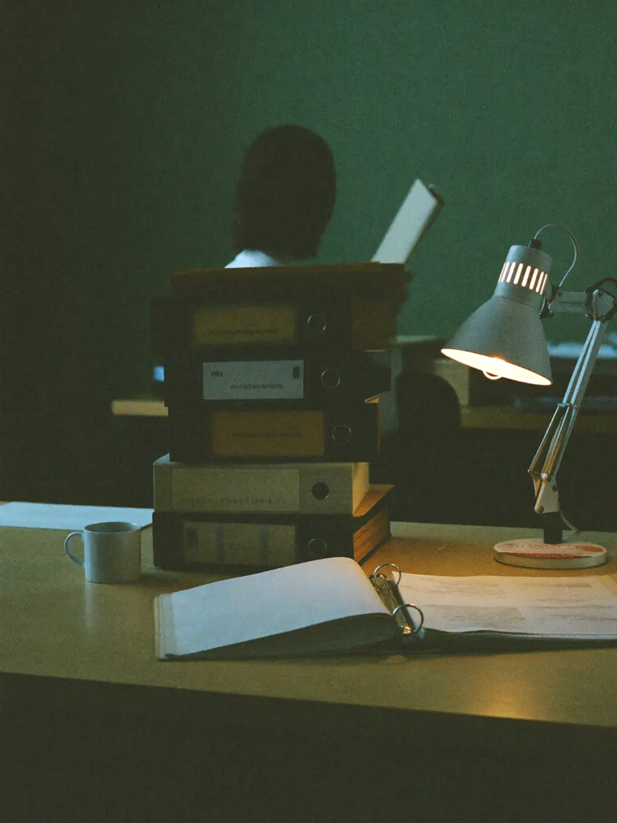A back-office desk mid-afternoon — binders, a mug, and one person working through the day's paperwork.