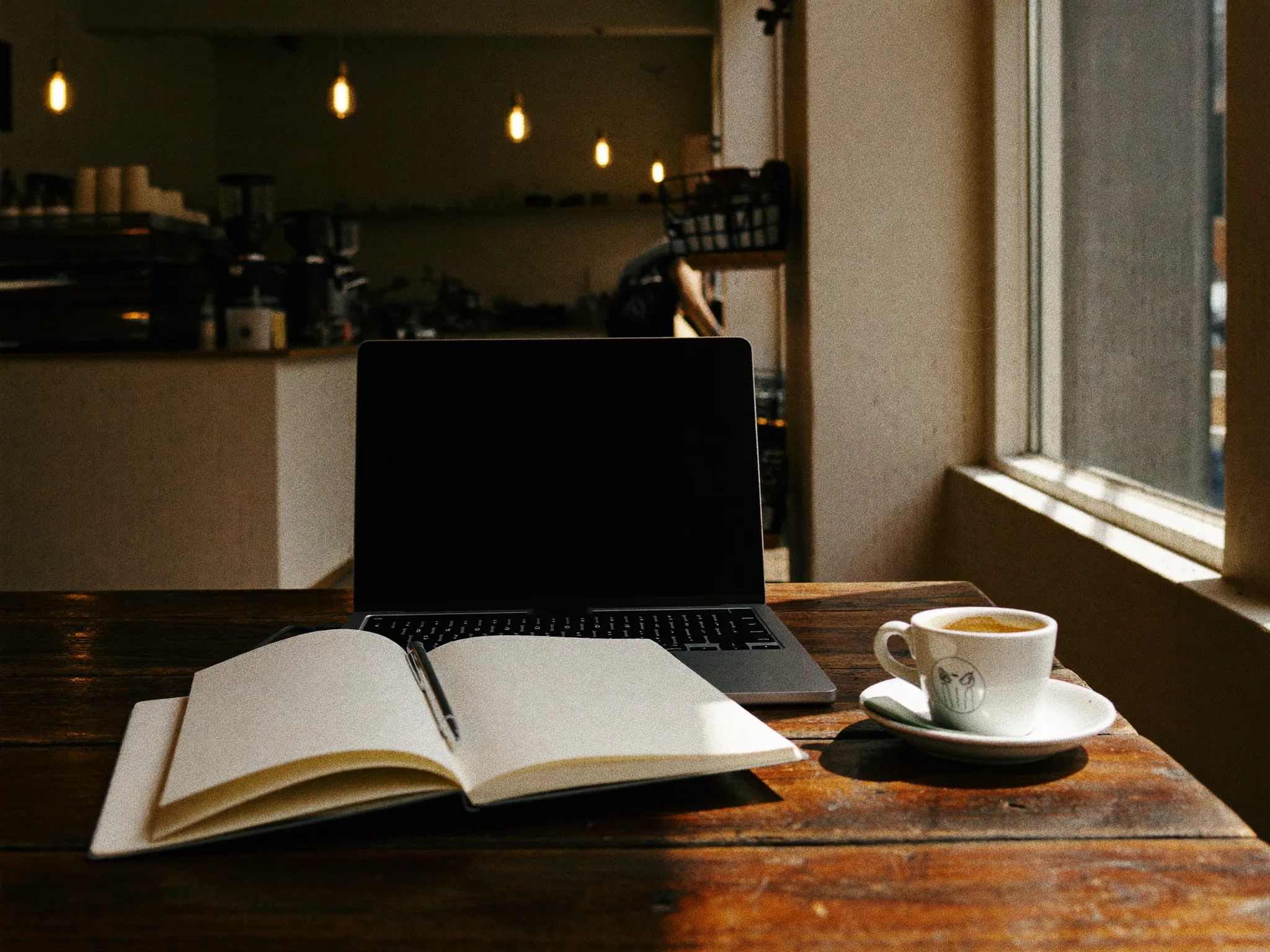 A table by the window after closing time — laptop still open, the day's paperwork unfinished