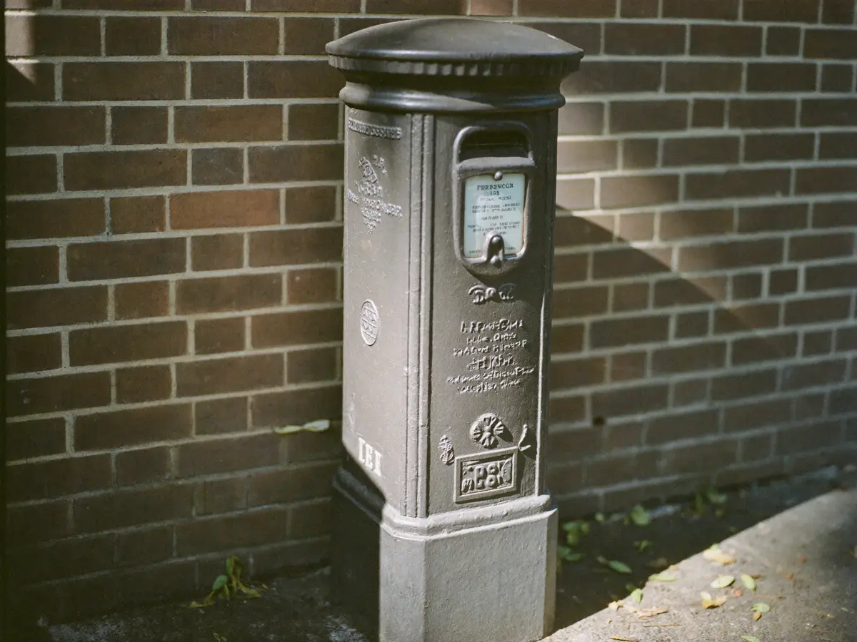 An old cast-iron postbox set into a brick wall in morning light.