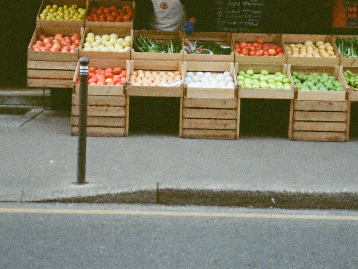 Crates of fruit and vegetables set out on the pavement outside a small shop.